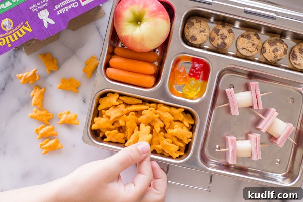 Southwestern-Style Mac and Cheese Cup Recipes for Game Day 5 A lunch box with an apple, carrot sticks, Annie's Cheddar Bunnies, Annie's Cookie Bites, some gummy snacks, and ham and cheese on toothpicks.