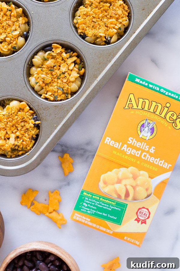 Southwestern-Style Mac and Cheese Cup Recipes for Game Day 6 Southwestern Mac and Cheese cups in a muffin pan, sitting next to a box of Annie's Shells & Real Aged Cheddar Macaroni & Cheese.