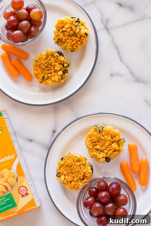 Southwestern-Style Mac and Cheese Cup Recipes for Game Day 7 Two plates with two Southwestern Mac and Cheese cups on each plate, along with a cup of grapes and some carrot sticks.