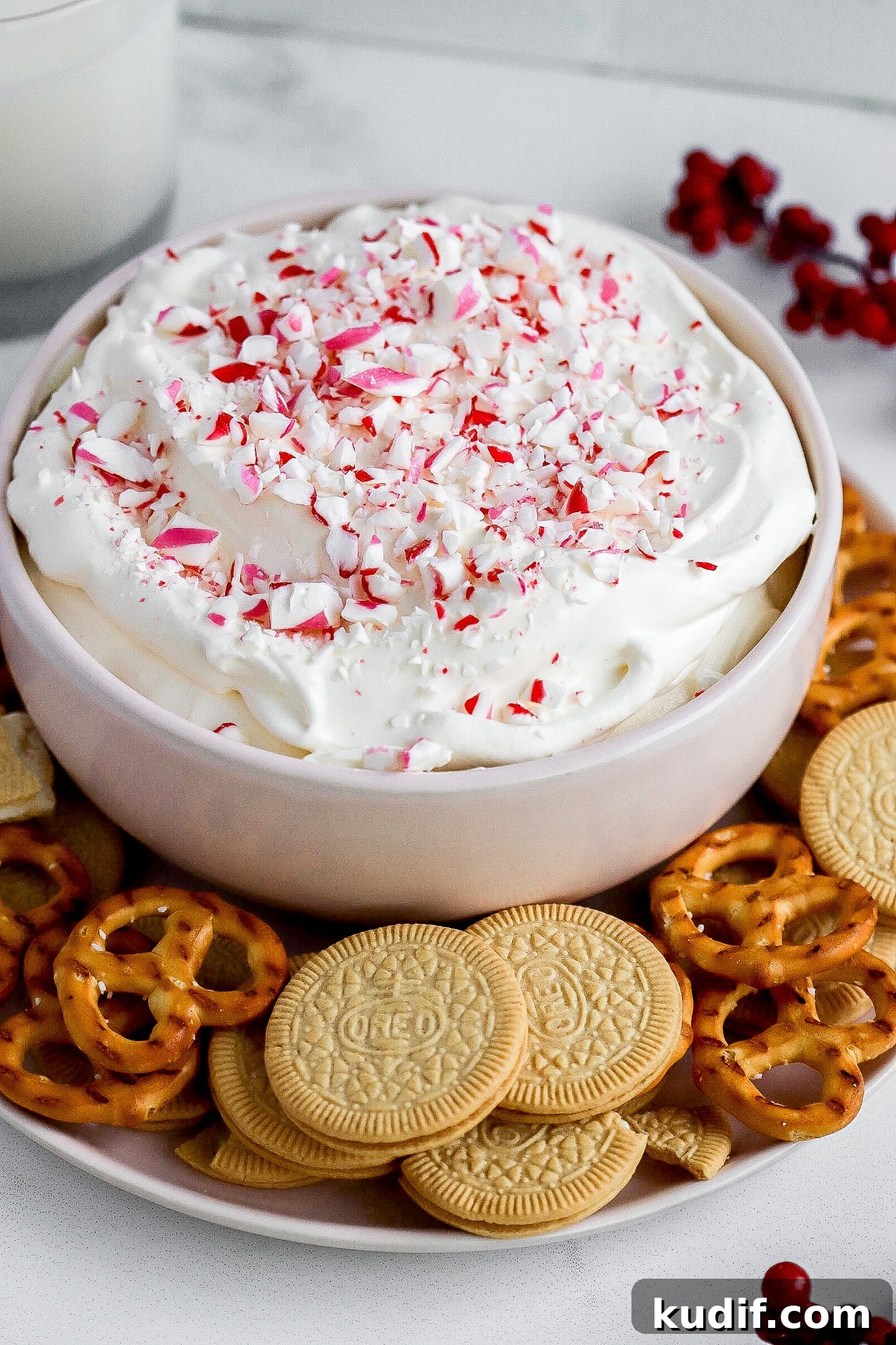 Peppermint Dessert Dip for Christmas Parties 3 Side view of peppermint cheesecake dip in small white bowl and vanilla cookies in foreground.
