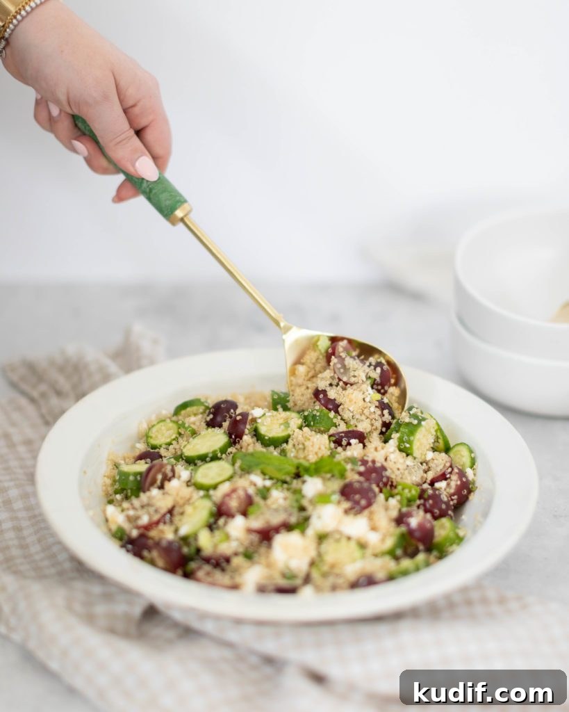 Minted Feta, Grape & Cucumber Quinoa Salad Recipe 2 hand scooping out minted feta quinoa salad