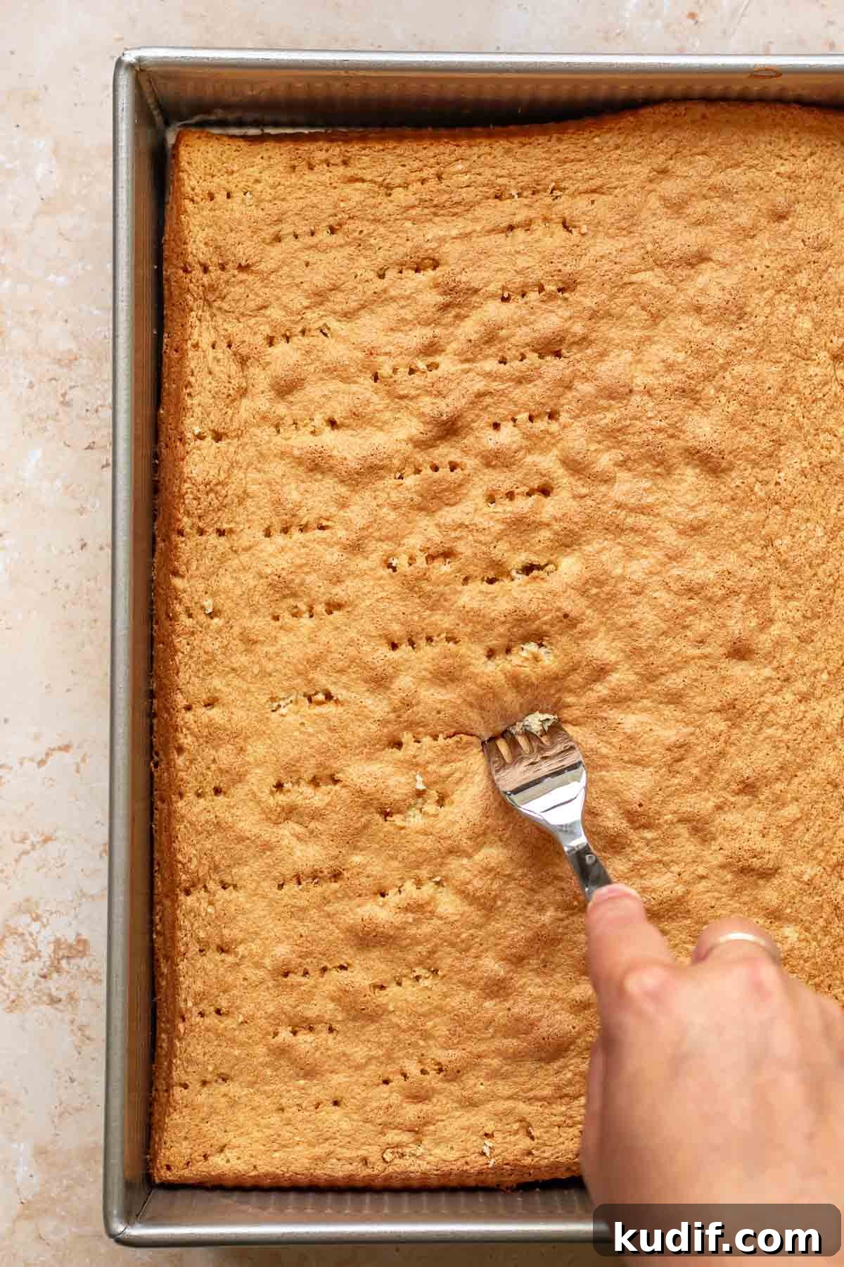 Coconut Tres Leches Cake Recipe — Moist Latin-Style Dessert 11 A fork creates pricks all over the baked sponge cake.