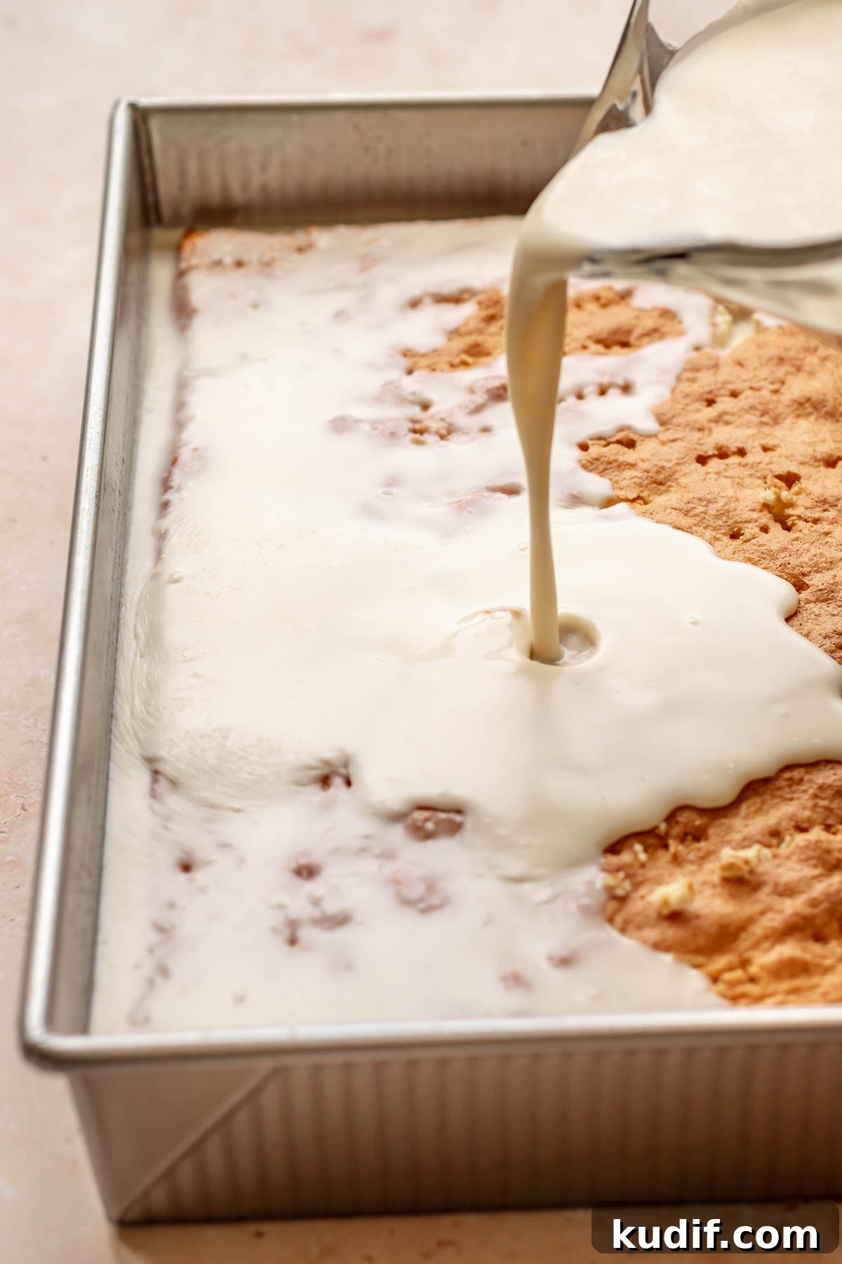 Coconut Tres Leches Cake Recipe — Moist Latin-Style Dessert 13 Milk mixture being poured onto the baked cake.
