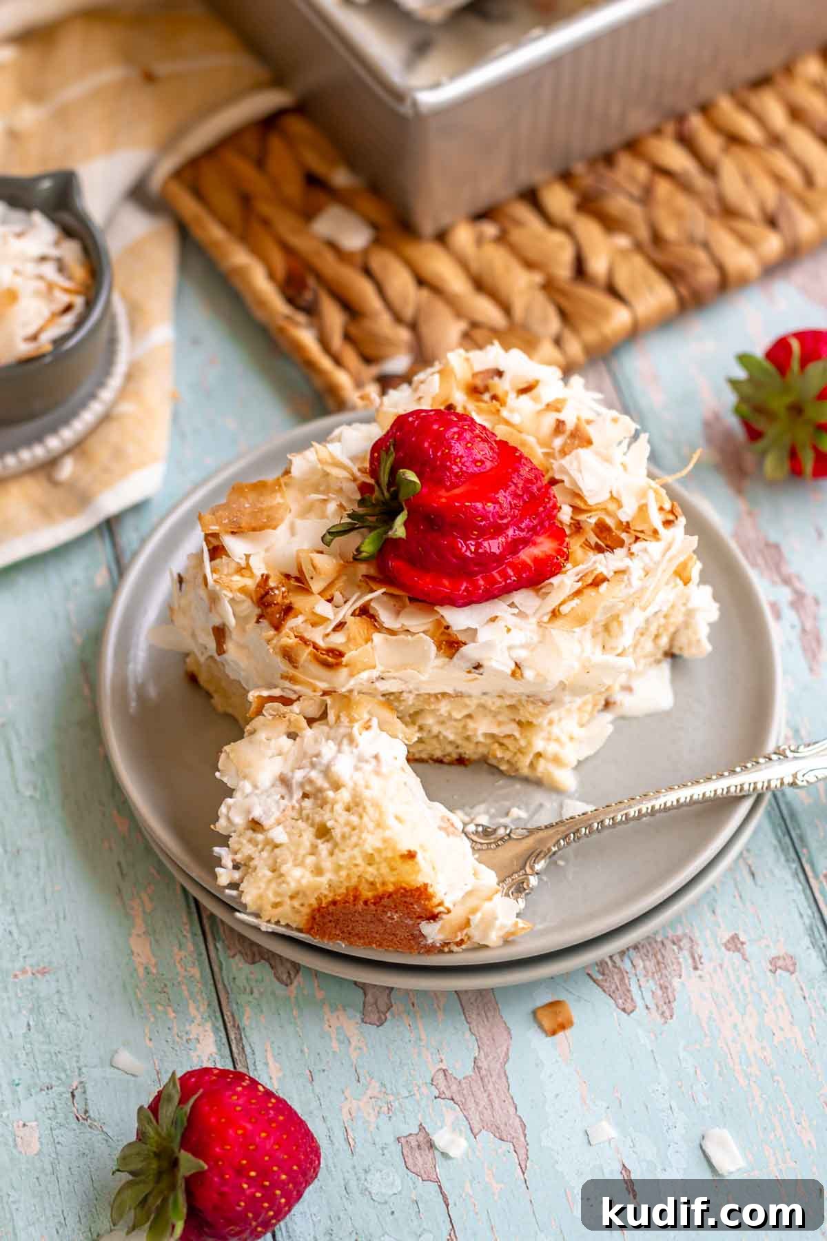 Coconut Tres Leches Cake Recipe — Moist Latin-Style Dessert 18 A slice of coconut tres leches cake on a plate with a fork removing a corner.