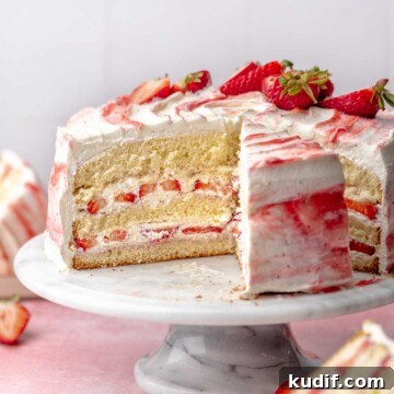 Strawberry shortcake cake sliced on a cake stand.