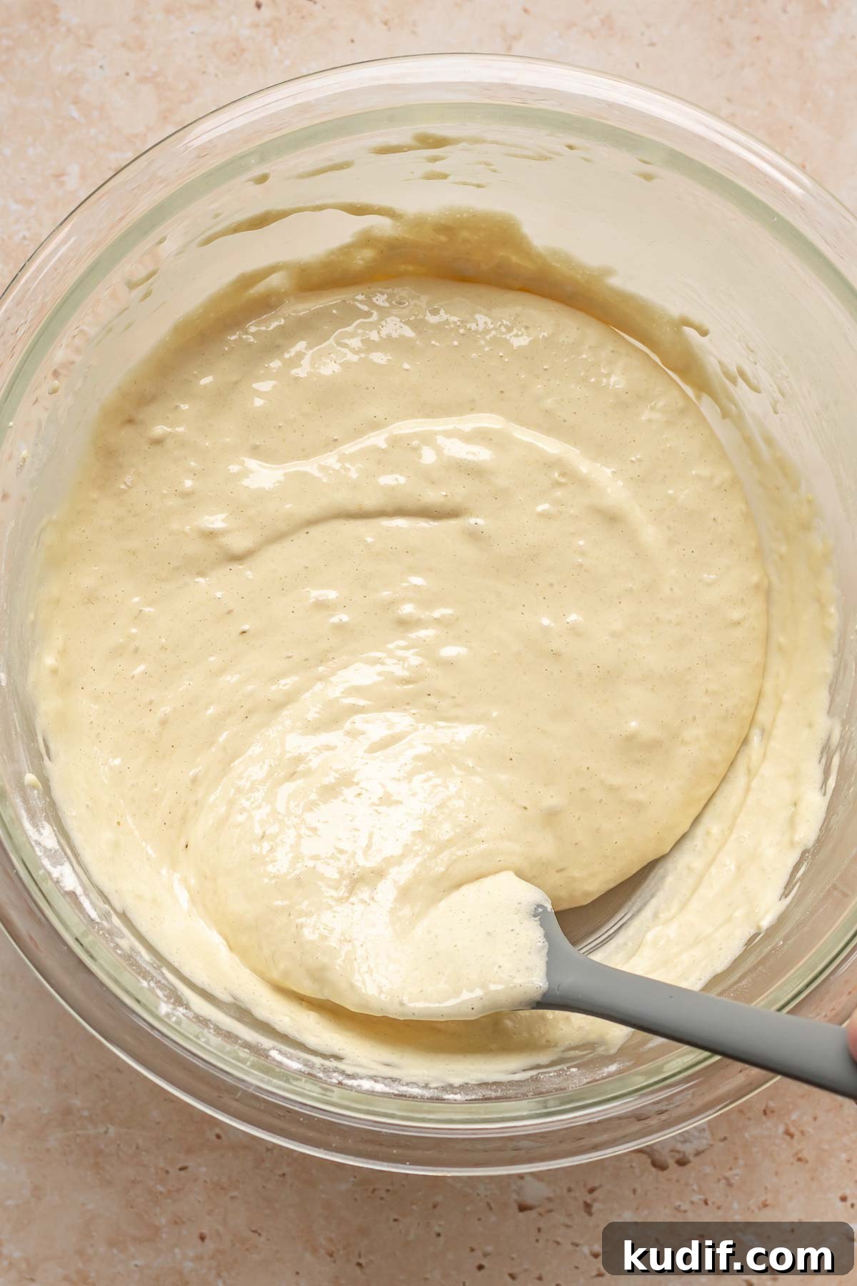 Coconut Tres Leches Cake Recipe — Moist Latin-Style Dessert 8 A spatula stirs sponge cake batter in a bowl.