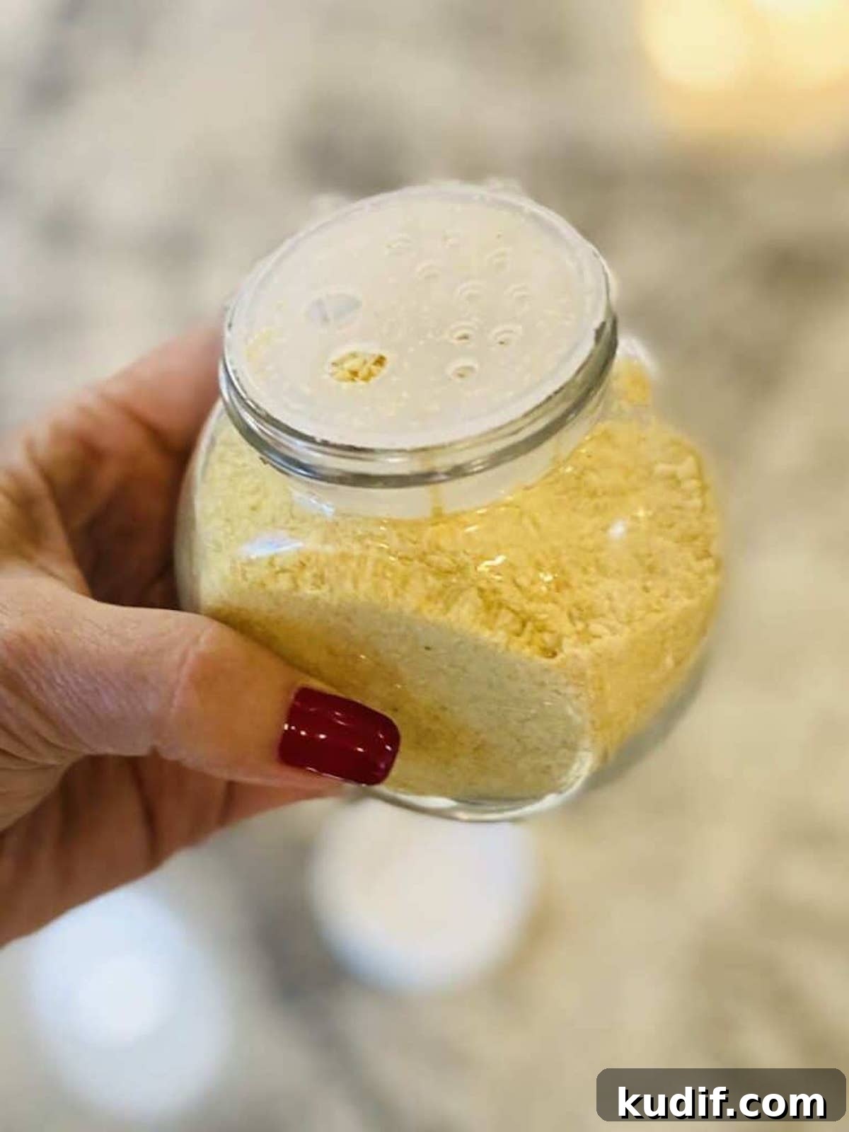 I am holding vegan parmesan cheese in a container.
