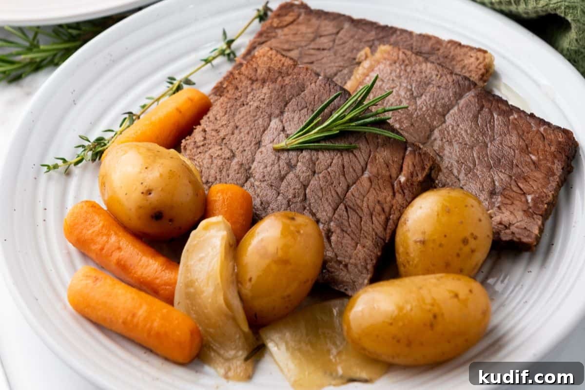 31 Delicious Recipes That Deliver Big Flavor with Little Effort 14 A plate of slow cooker rump roast with potatoes, carrots, onions, and a sprig of rosemary on a white dish.