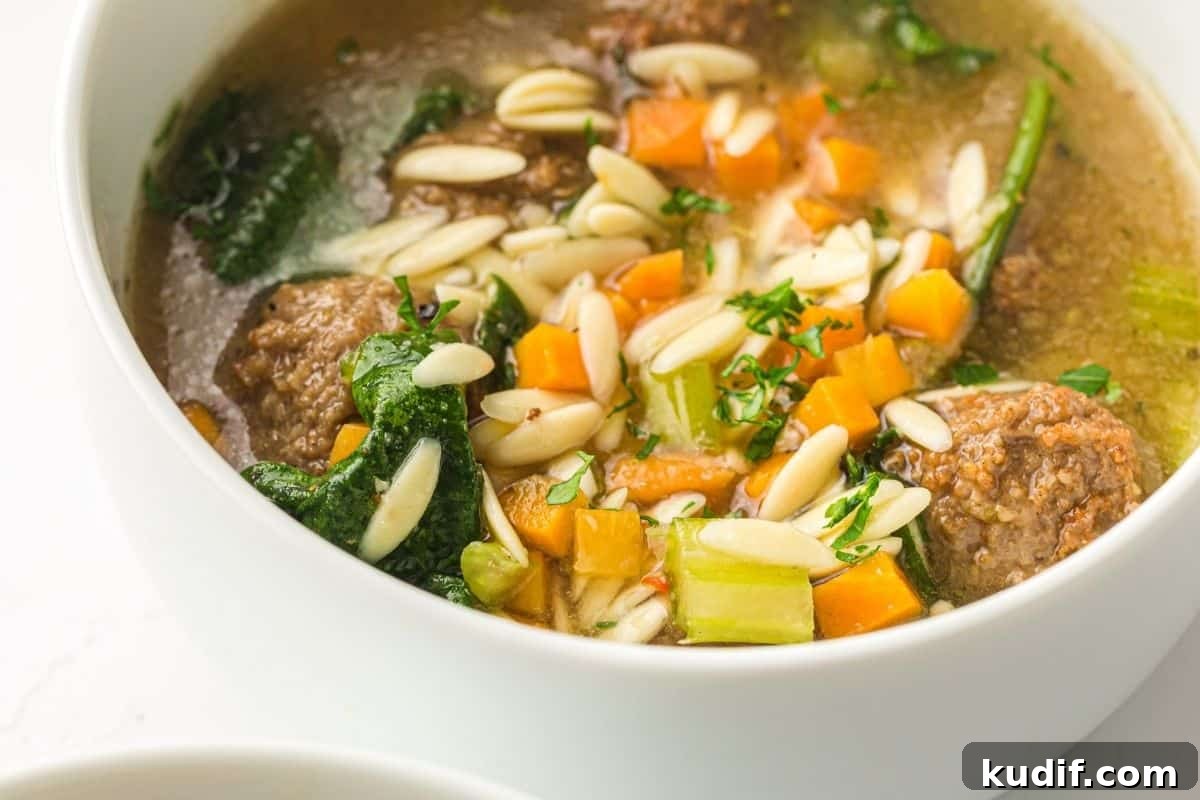 31 Delicious Recipes That Deliver Big Flavor with Little Effort 18 A close-up of a spoon holding a meatball in a bowl of Slow Cooker Italian Wedding Soup.