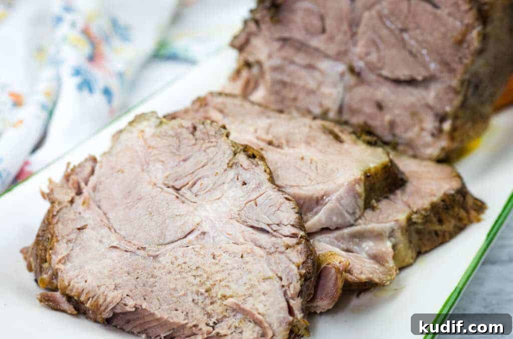 31 Delicious Recipes That Deliver Big Flavor with Little Effort 28 Sliced Herb-Crusted Pork Roast on a rectangular white plate with a floral napkin in the background.