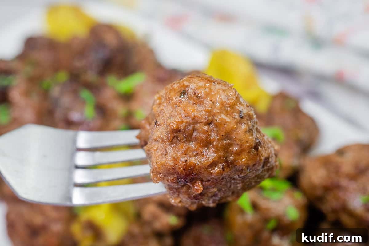 31 Delicious Recipes That Deliver Big Flavor with Little Effort 6 A close-up of a meatball on a fork, with more meatballs in the background.