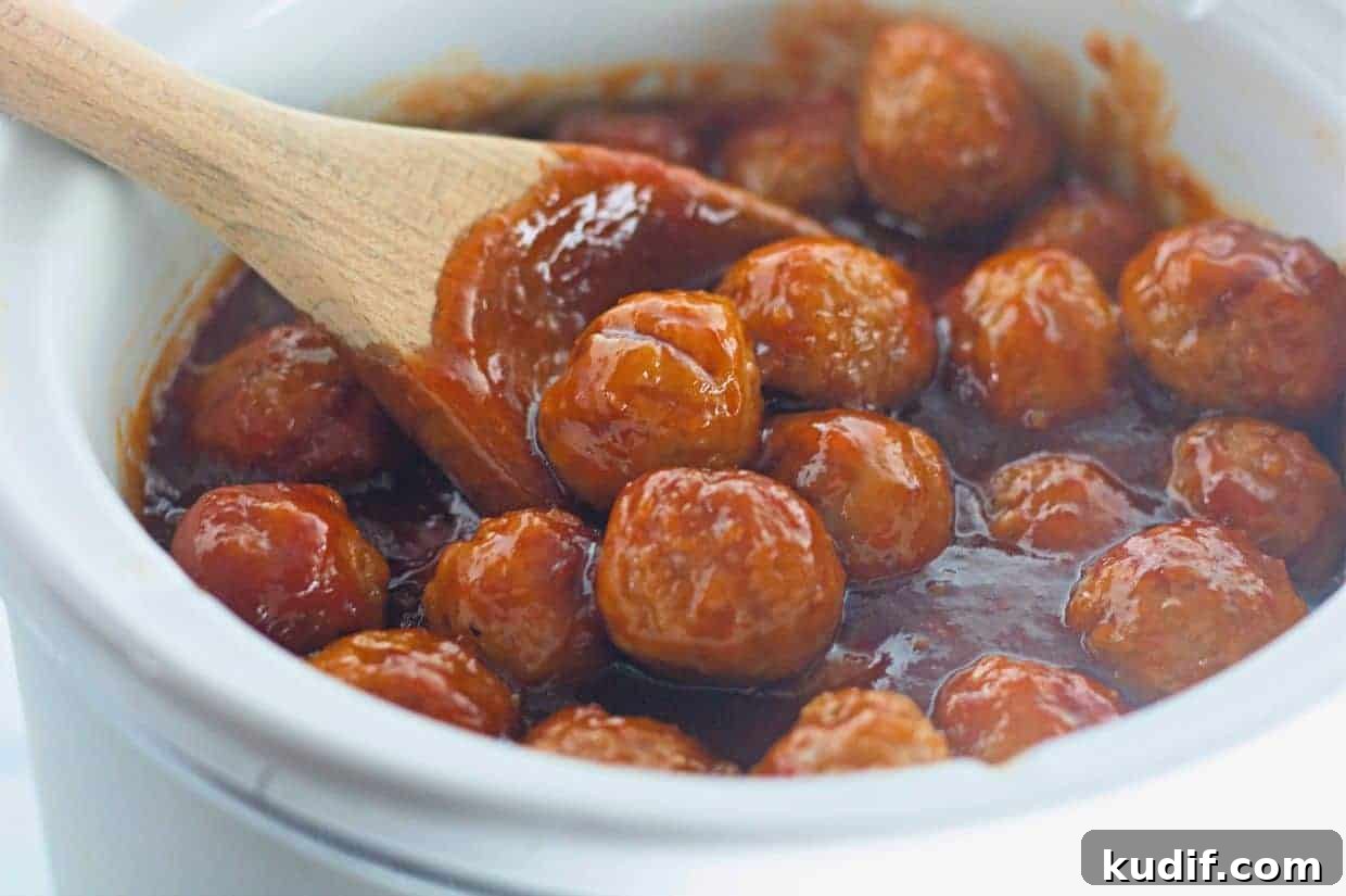 31 Delicious Recipes That Deliver Big Flavor with Little Effort 8 Honey-Garlic Meatballs in a thick red sauce are being stirred with a wooden spoon in a white ceramic pot.