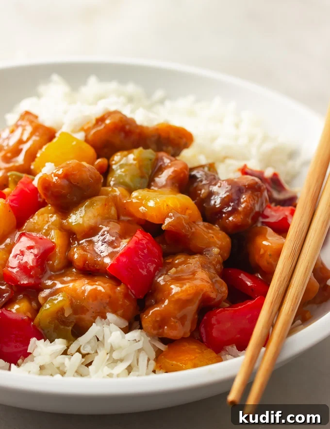 Sweet and Sour Chicken Recipe That Beats Takeout 2 A plate of sweet and sour chicken with bell peppers, onions, pineapples tossed in a sweet and savory sauce over rice.