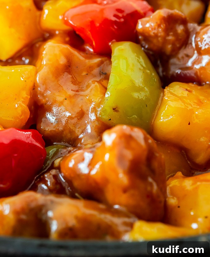 Sweet and Sour Chicken Recipe That Beats Takeout 8 A plate of sweet and sour chicken with bell peppers, onions, pineapples tossed in a sweet and savory sauce over rice.
