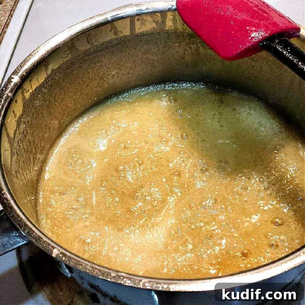 Classic Old-Fashioned Hot Fudge Sauce Recipe 8 A pot of boiling cream, sugar, and butter that is a light caramel color.