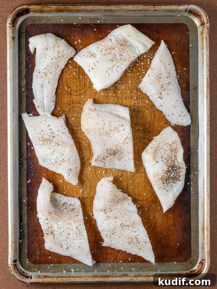Mediterranean Sheet-Pan Baked Cod with Parsley Garlic Oil 5 cod fillets sprinkled with salt and pepper on a plate