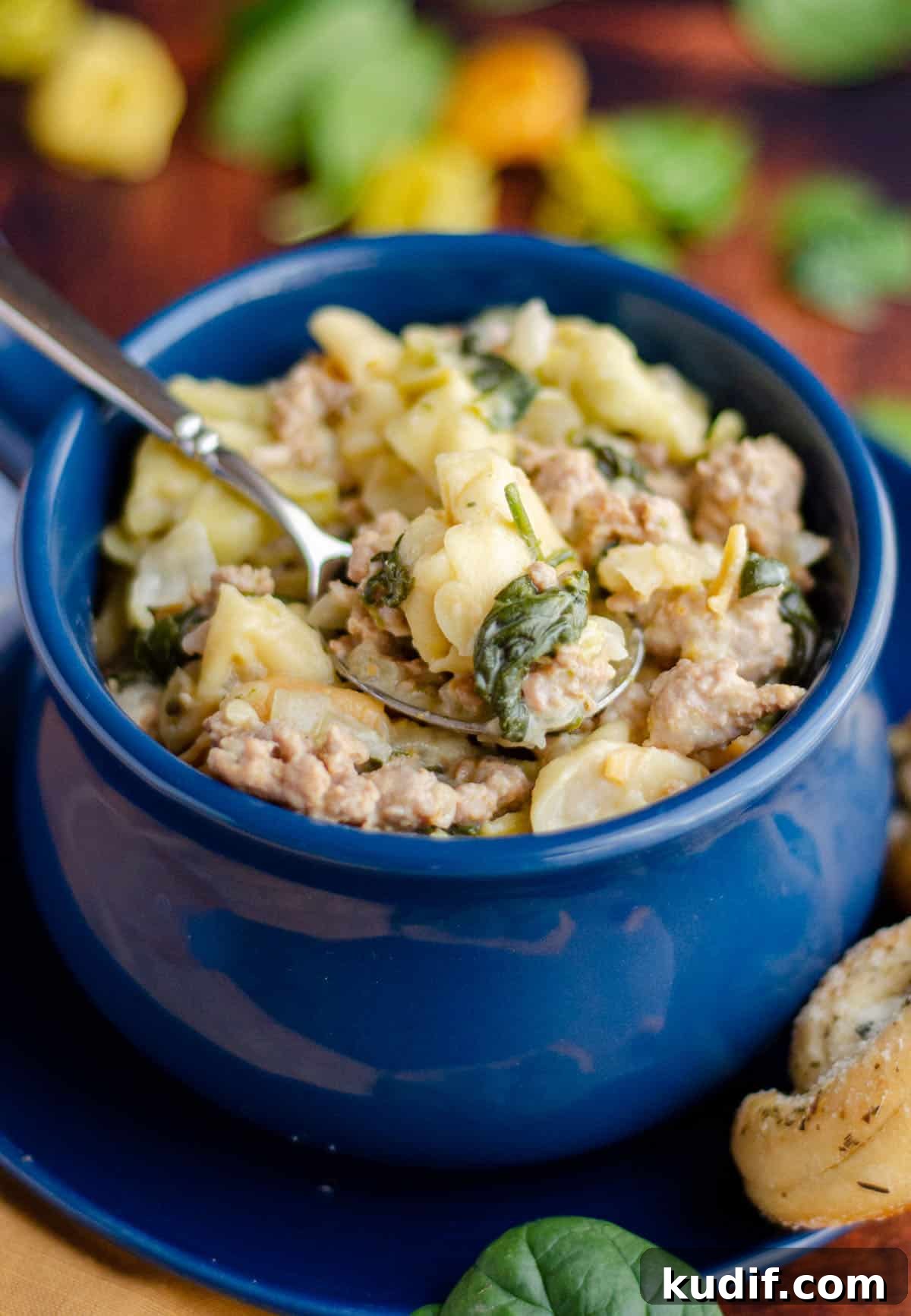 Hearty Italian Sausage Tortellini Soup Recipe 7 sausage tortellini soup in a blue bowl with a spoon scooping out a bite