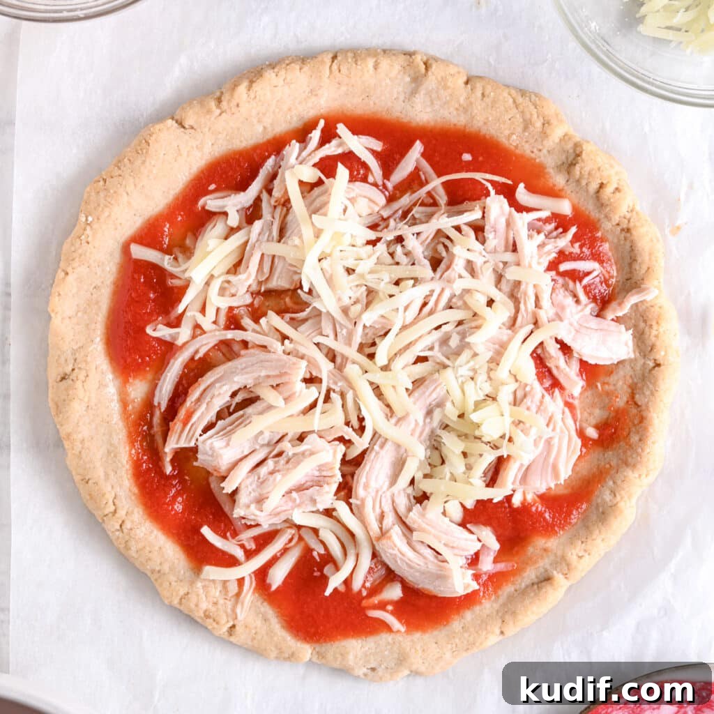 High-Protein Pizza Recipe for Muscle Gain and Recovery 11 Protein pizza crust topped with pizza sauce, shredded cheese and shredded chicken ready baking