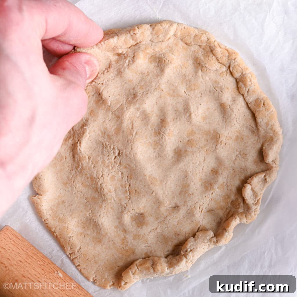 High-Protein Pizza Recipe for Muscle Gain and Recovery 7 Rolling dough with rolling pin and hands, crafting the borders with fingers.