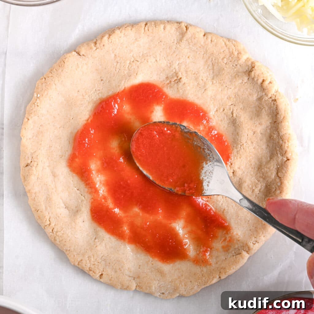 High-Protein Pizza Recipe for Muscle Gain and Recovery 9 Spreading tomato sauce on top of Greek yogurt protein crust