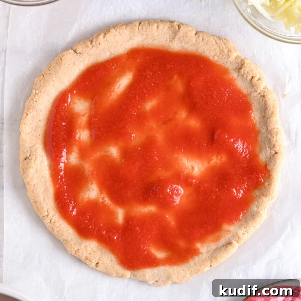 High-Protein Pizza Recipe for Muscle Gain and Recovery 10 Greek yogurt pizza base topped with homemade pizza sauce before adding cheese and toppings.