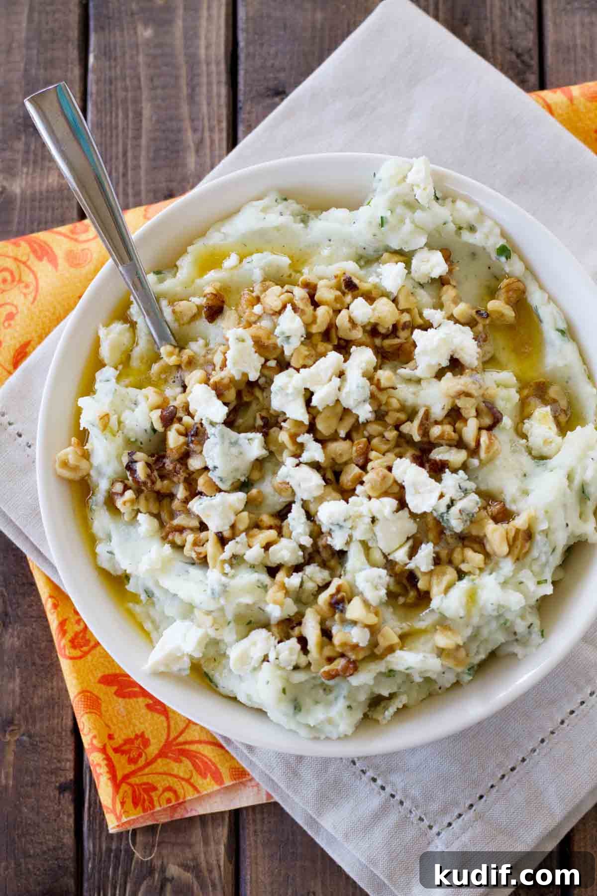 Bowl filled with Blue Cheese and Walnut Mashed Potatoes topped with walnuts, blue cheese, and brown butter.
