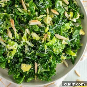 Kale crunch salad on plate with fork to the side and bowl of vinaigrette.