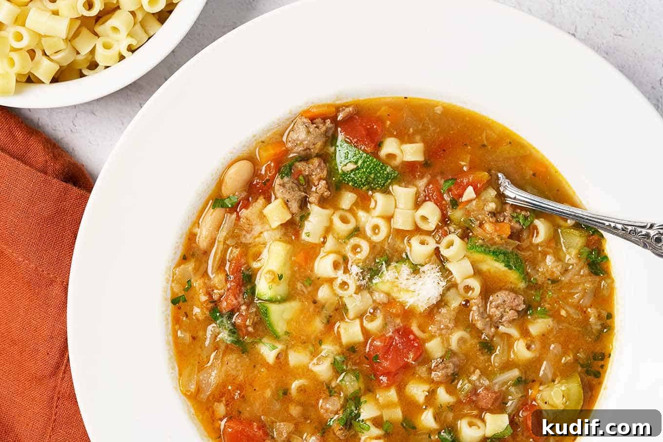 Sausage Minestrone Soup with Vegetables and Beans 4 A close view of homemade minestrone soup with Italian sausage, tomatoes, zucchini, beans, cabbage, carrots, pasta, and more.