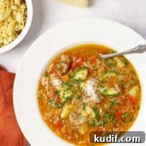 Sausage Minestrone Soup with Vegetables and Beans 5 A bowl of hearty minestrone soup with assorted vegetables and pasta topped with grated cheese, fresh parsley, ditalini, and a wedge of Parmesan on the side.
