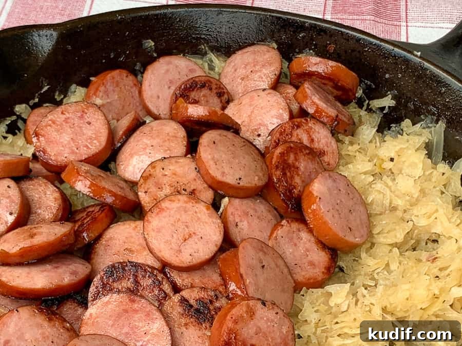 Kielbasa and Sauerkraut Recipes: Classic Polish Sausage Dishes 4 Coins of smoked Kielbasa sausage on sauerkraut in cast iron skillet.