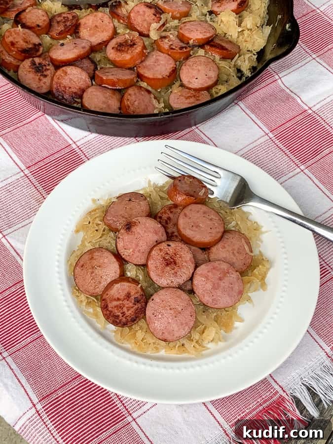 Kielbasa and Sauerkraut Recipes: Classic Polish Sausage Dishes 6 Easy sauerkraut and Polish sausage on a plate with a fork and skillet in the background.