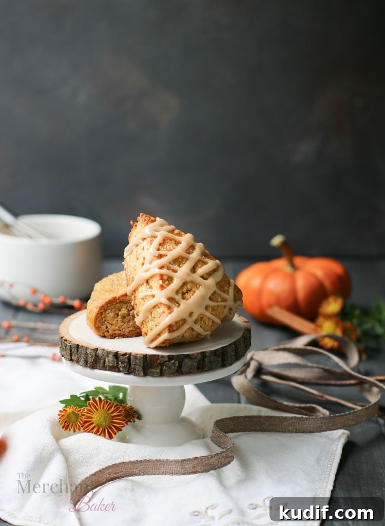 Pumpkin Scones Recipe: Flaky Spiced Scones for Fall Baking 2 Two of the best pumpkin scones displayed on a raw wood slab by themerchantbaker.com