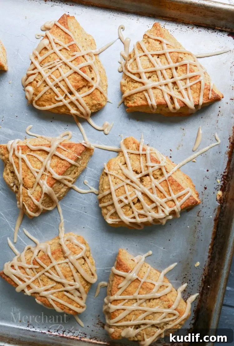 Pumpkin Scones Recipe: Flaky Spiced Scones for Fall Baking 7 The best pumpkin scones on a baking sheet drizzled with cinnamon icing by themerchantbaker.com