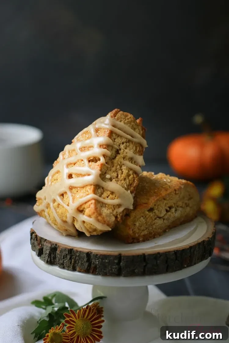 Pumpkin Scones Recipe: Flaky Spiced Scones for Fall Baking 3 Two of the best pumpkin scones displayed on a raw wood slab by themerchantbaker.com