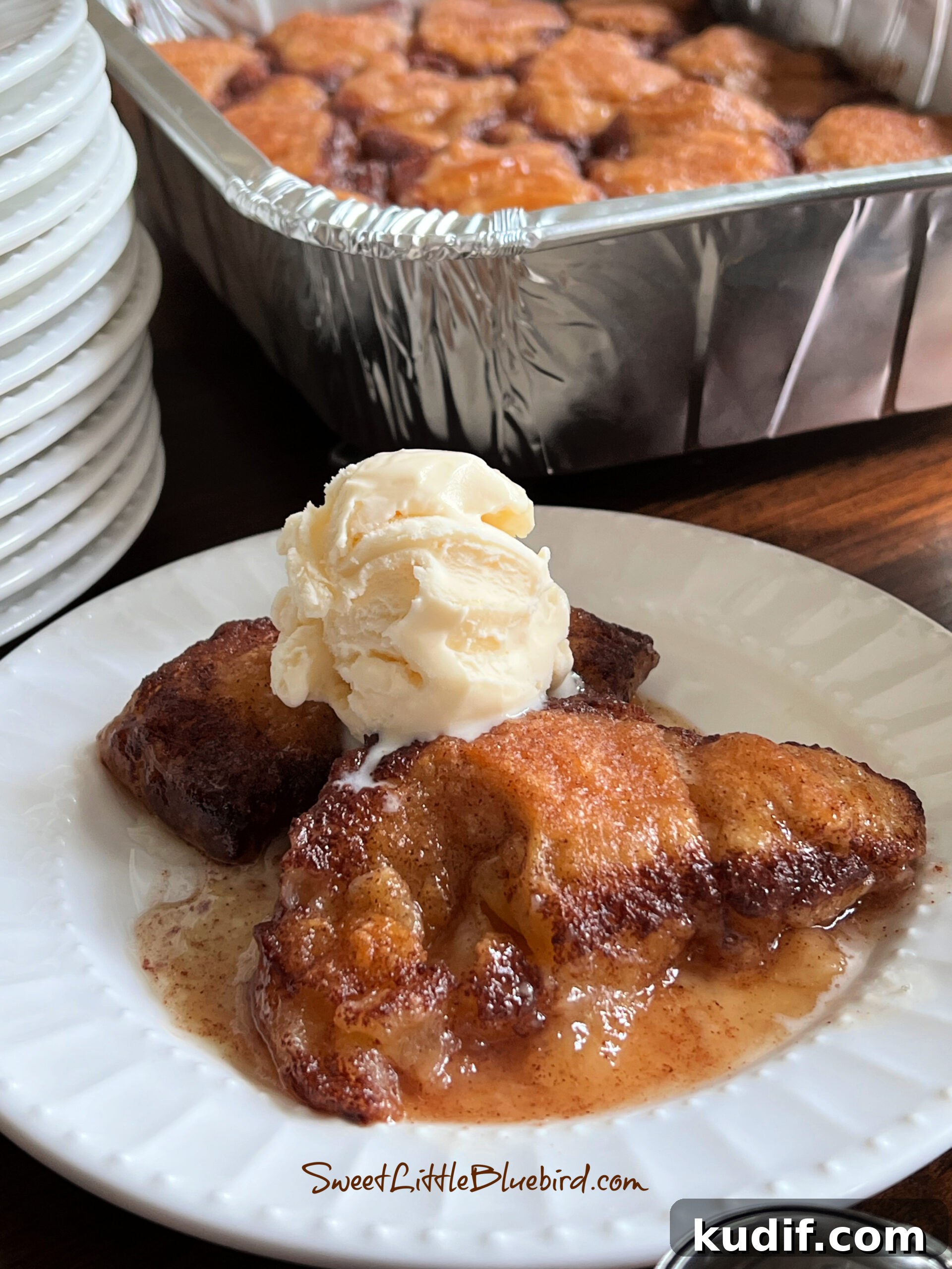 Crescent Roll Peach Dumplings with Warm Cinnamon Sauce 2 Two peach dumplings on a plate topped with vanilla ice cream.