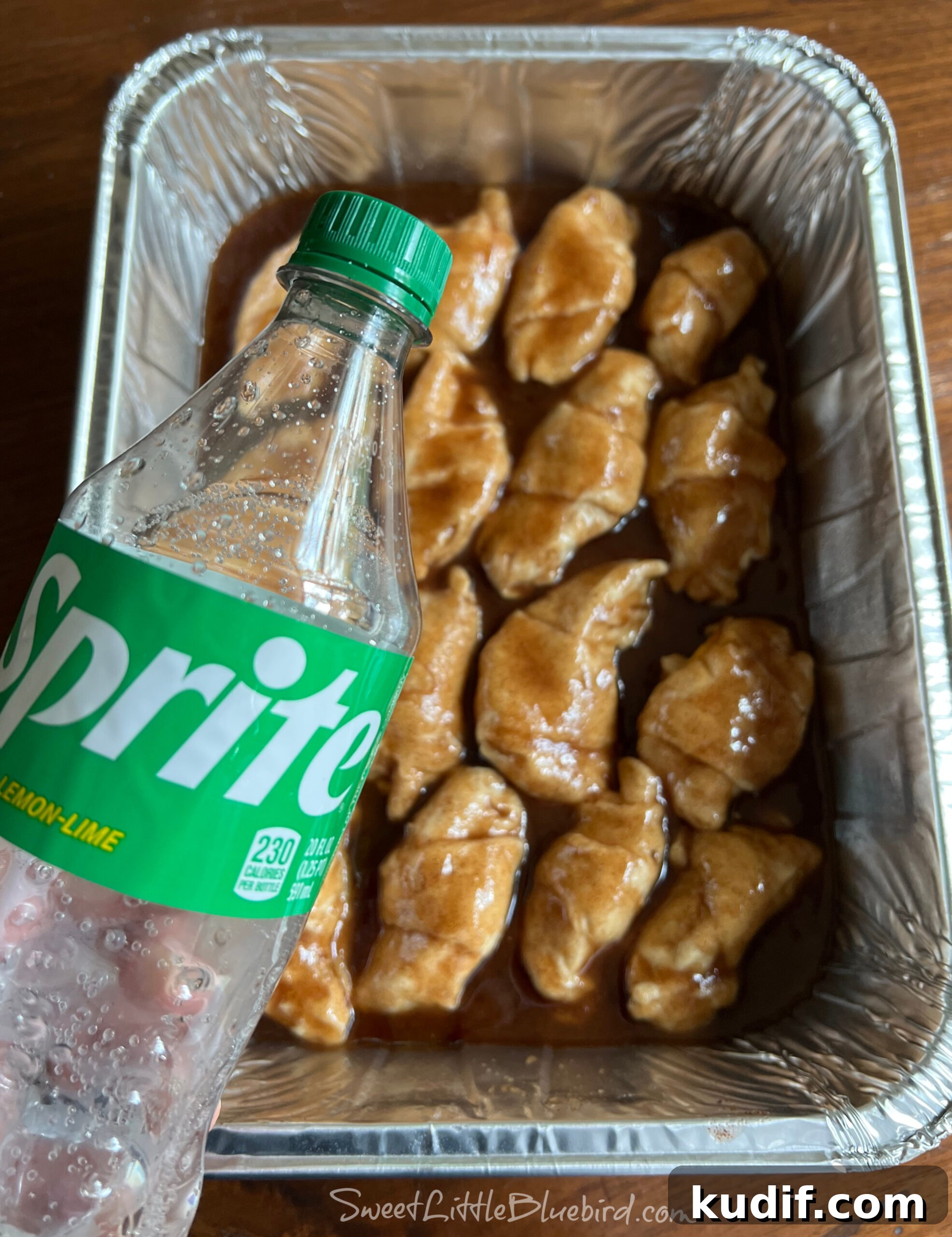 Crescent Roll Peach Dumplings with Warm Cinnamon Sauce 7 A hand holding a bottle of Sprite ready to pour around the dumplings.