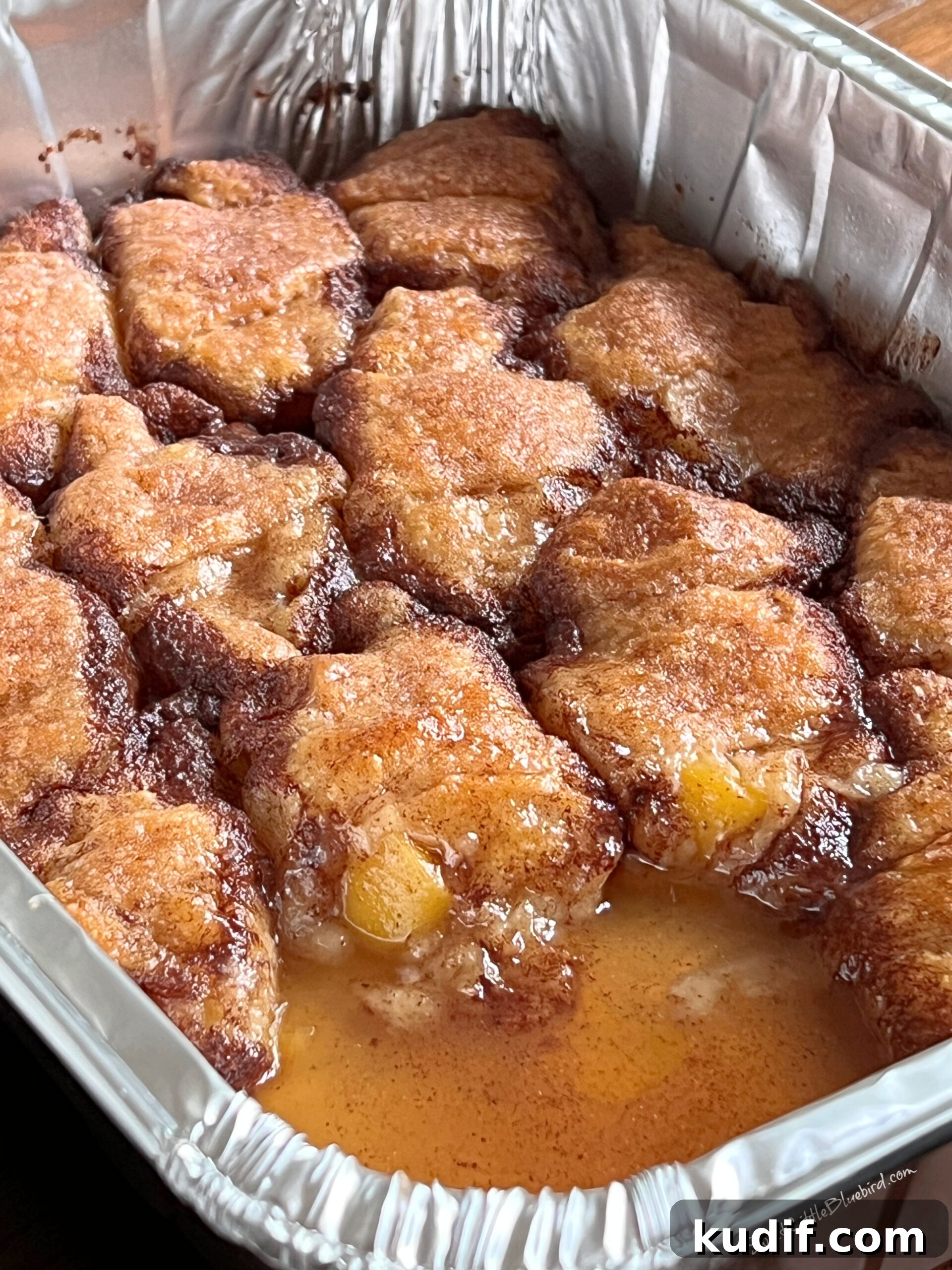 Crescent Roll Peach Dumplings with Warm Cinnamon Sauce 9 Baked peach dumplings in the pan with one removed.