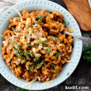 Cheesy Taco & Cream Cheese Pasta Recipe for Weeknight Dinners 10 one pot cheesy taco pasta in a blue bowl topped with cheese and cilantro