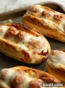 close up shot of meatball sub on oven tray surrounded by 4 others