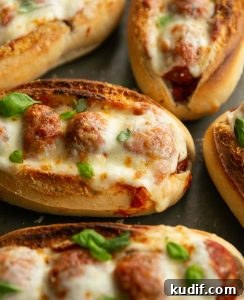 close up shot of meatball sub on oven tray garnished with fresh basil