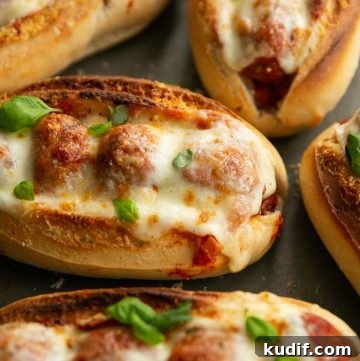 close up shot of meatball sub on oven tray garnished with fresh basil