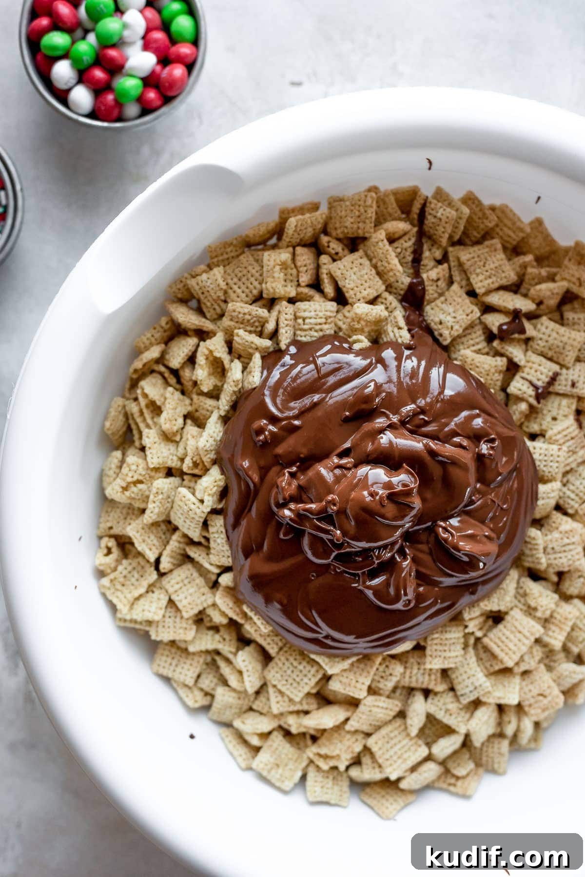 Festive Christmas Puppy Chow Snack Mix Recipe 4 Chex cereal in bowl topped with mix of melted chocolate, peanut butter, vanilla, and butter