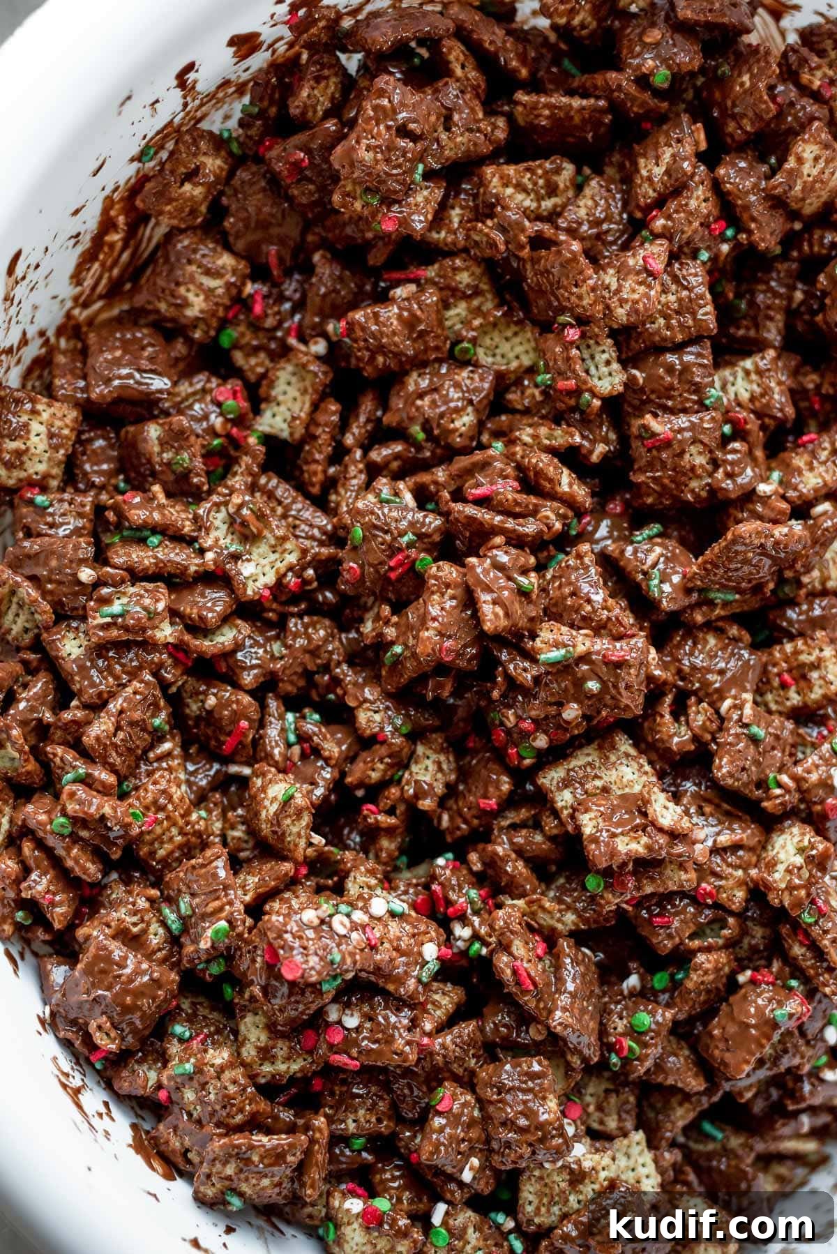 Festive Christmas Puppy Chow Snack Mix Recipe 5 cereal mixed with chocolate and peanut butter and sprinkles for christmas muddy buddies