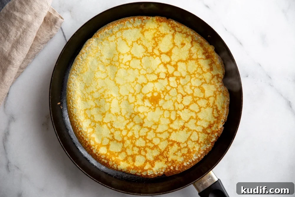 A cooked crepe in a non-stick skillet.