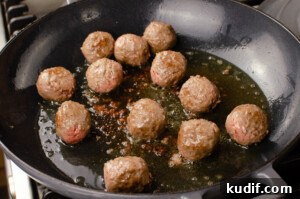 Spicy One-Pot Meatball Pasta Recipe for Quick Dinners 3 Beef meatballs cooking in olive oil in a grey cast iron pan