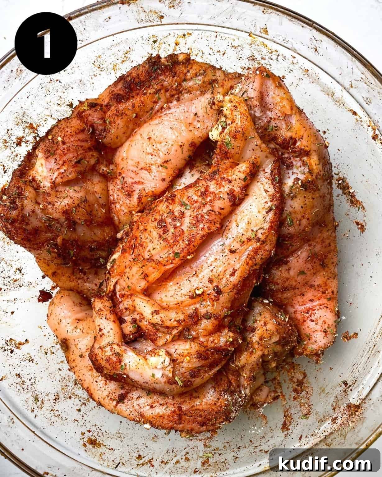 boneless skinless chicken breasts in a bowl coated with seasonings.