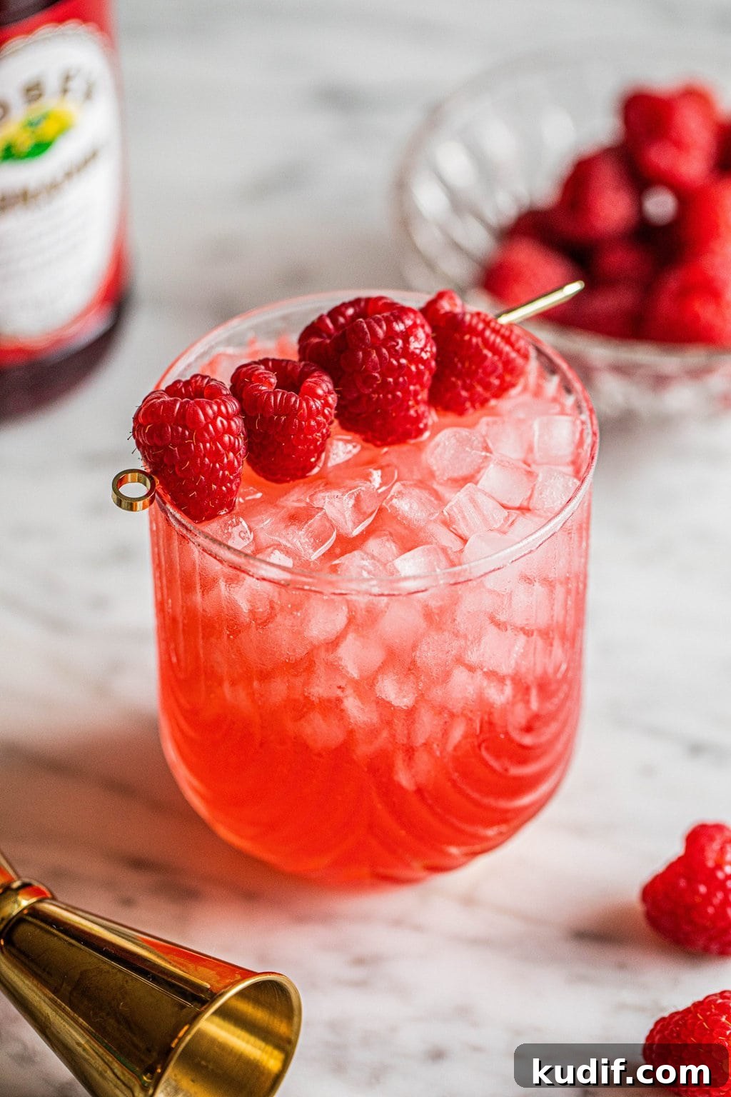 Raspberry Vodka Champagne Cocktail Recipe for Celebrations 2 vodka champagne cocktail in glass garnished with raspberries on gold skewer