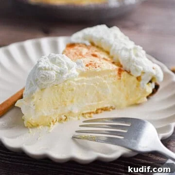 A slice of the no-bake eggnog pie is on a plate with a fork and a cinnamon stick.