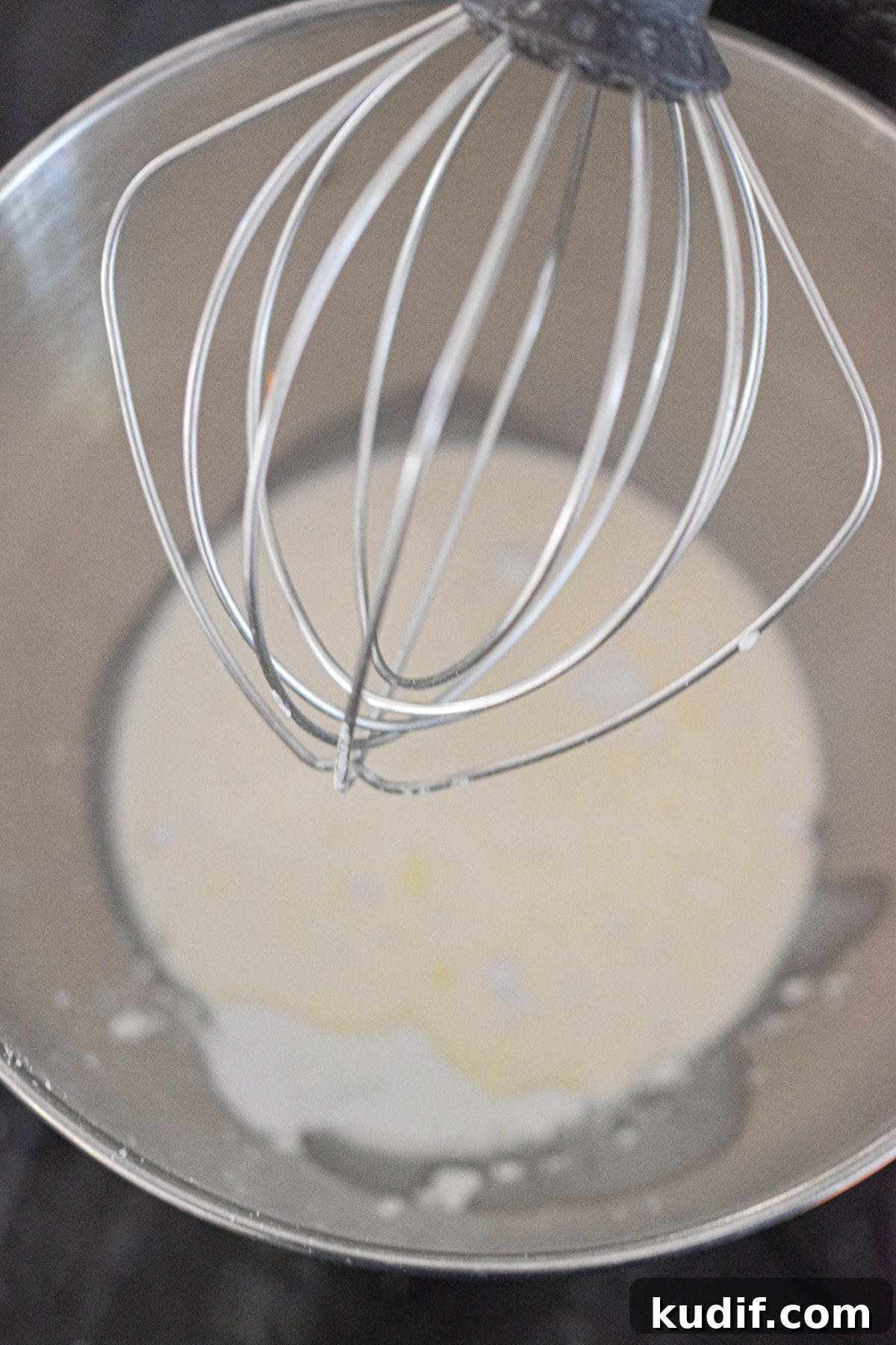 The whipped cream is in the bowl of a stand mixer.