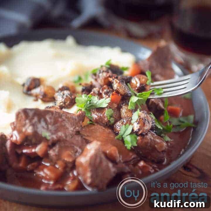 A square photo with a gray plate, mashed potatoes, French beef bourguignon with parsley.
